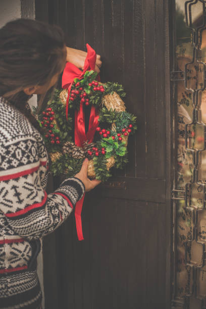istock Woman hanging Christmas wreath on front door 1080354342