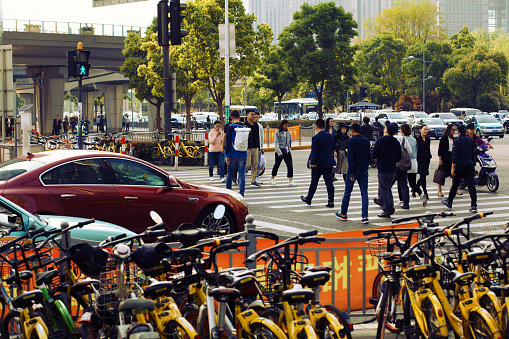 Shanghai, China - April 25, 2018: Commuters crossing the street at rush hour in Shanghai.