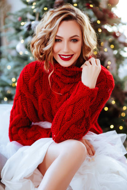 istock smiling woman in red sweater over christmas tree background 1080372378
