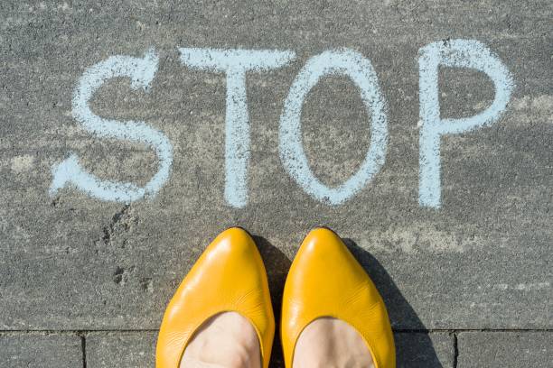 istock Female feet with text stop written on asphalt 1080377976