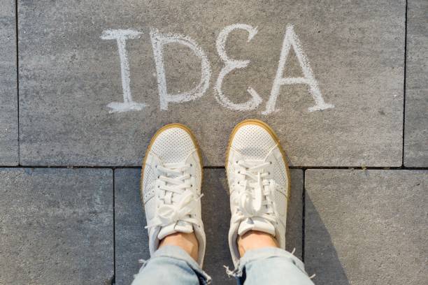 istock View from above, female feet with text idea written on grey sidewalk 1080378442