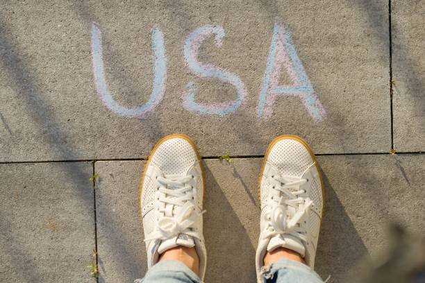 istock View from above, female feet with text USA written on grey sidewalk 1080378520