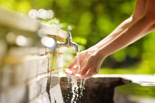 femme se laver les mains dans une fontaine de la ville de rome - fontaine photos et images de collection