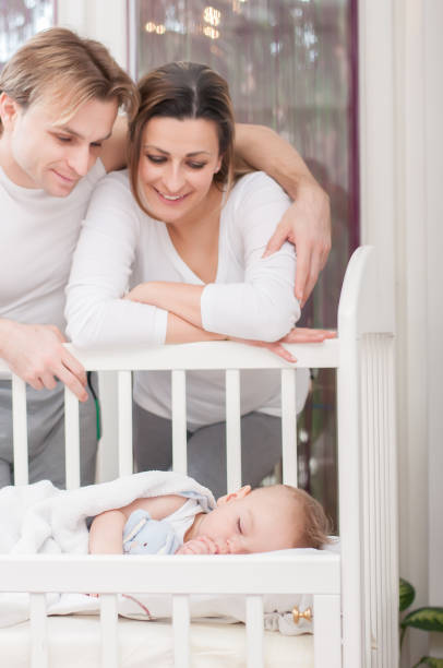 istock Happy parents standing beside the baby's bed. Happiness and pride. 1080384196
