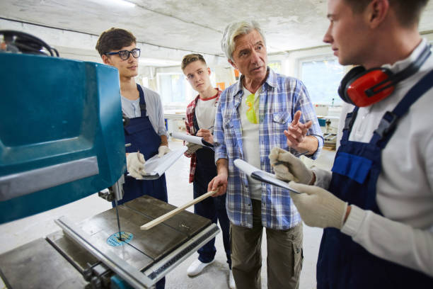 carpenter explaining how to works with drilling machine - trainee mechanic engineer student imagens e fotografias de stock