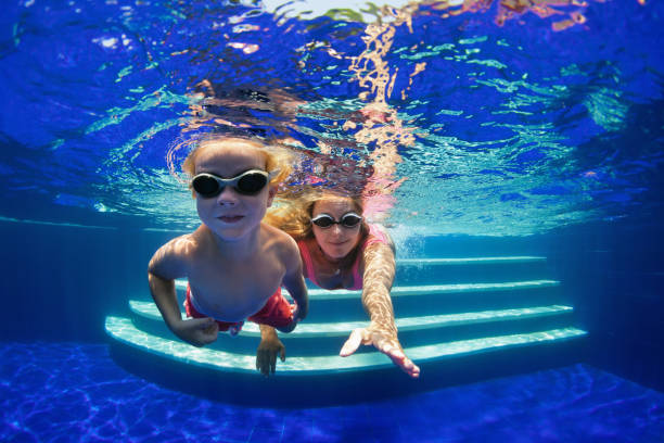 istock Child with mother dive in swimming pool 1080387750