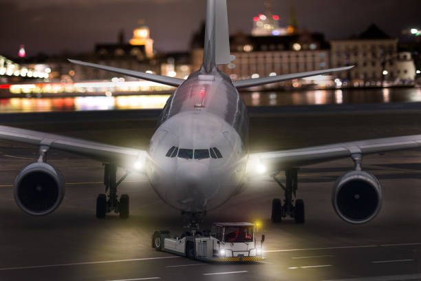 istock an airplane beeing towed at an airport at night composing 1080389108