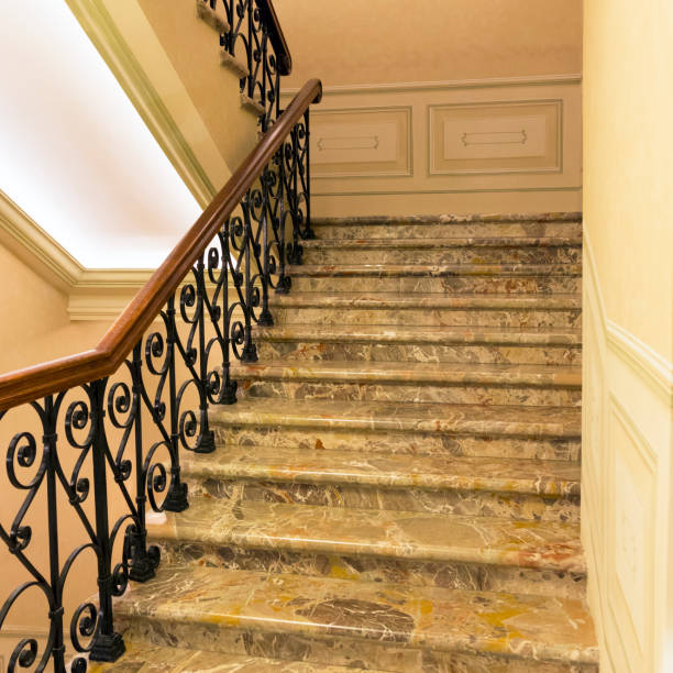 scala in marmo con ringhiera in ferro battuto e corrimano in legno - staircase indoors wrought iron mansion foto e immagini stock