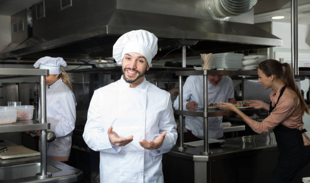 istock Chef in kitchen on background with employees 1080395944