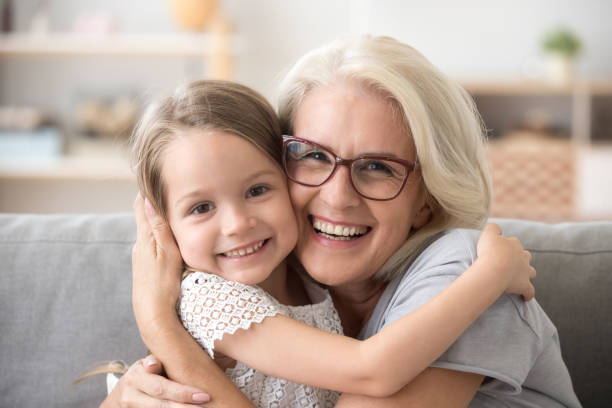 abuela más feliz abrazando a niña nieto mirando a cámara - aging process women human face daughter fotografías e imágenes de stock