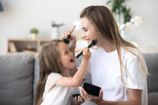 istock Smiling mom and happy kid daughter doing makeup together 1080412624