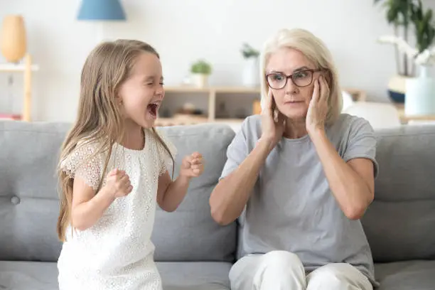 Photo of Shocked grandma closing ears not to hear stubborn granddaughter screaming