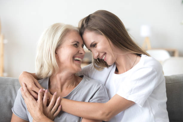Happy loving older mother and grown millennial daughter laughing embracing Happy loving older mature mother and grown millennial daughter laughing embracing, caring smiling young woman embracing happy senior middle aged mom having fun at home spending time together obedience photos stock pictures, royalty-free photos & images