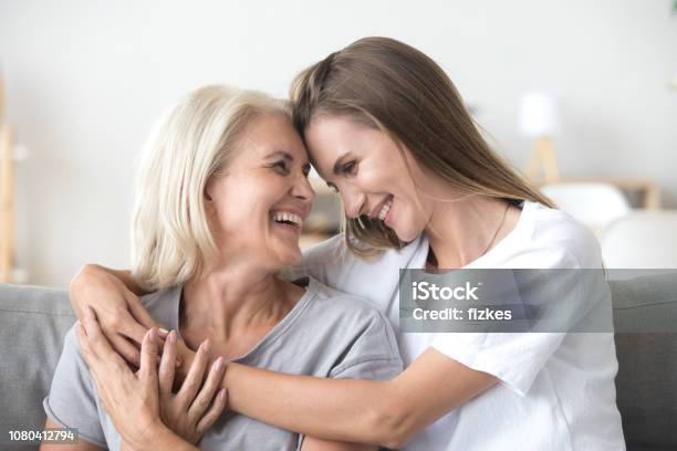 Happy Loving Older Mother And Grown Millennial Daughter Laughing Embracing Stock Photo - Download Image Now