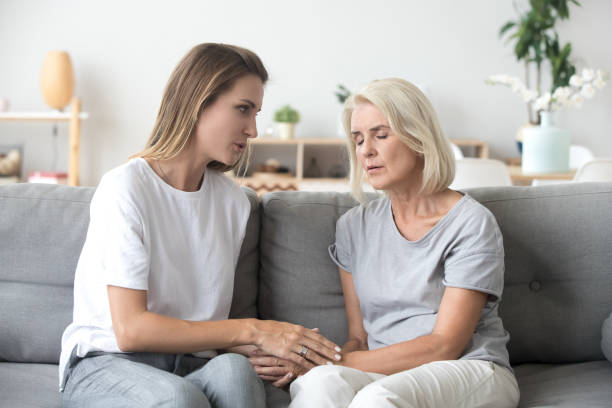 Adult daughter talking to sad old mother supporting upset woman Loving adult daughter talking to sad old mother holding hand comforting upset older woman having problem, young caregiver helping senior patient, support, empathy and care to elderly parent concept woman comforting depressed friend stock pictures, royalty-free photos & images