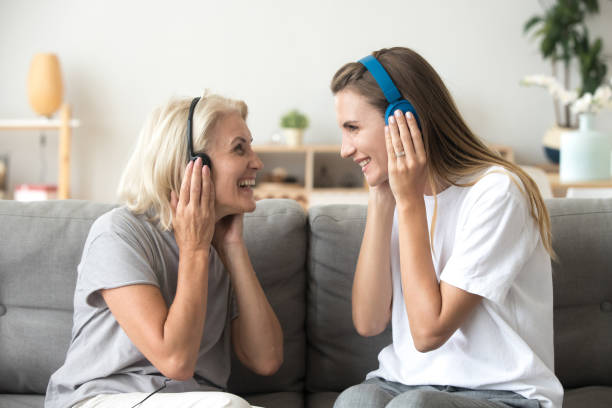 feliz madre senior y adulto hija escuchar música en auriculares - fun time audio fotografías e imágenes de stock