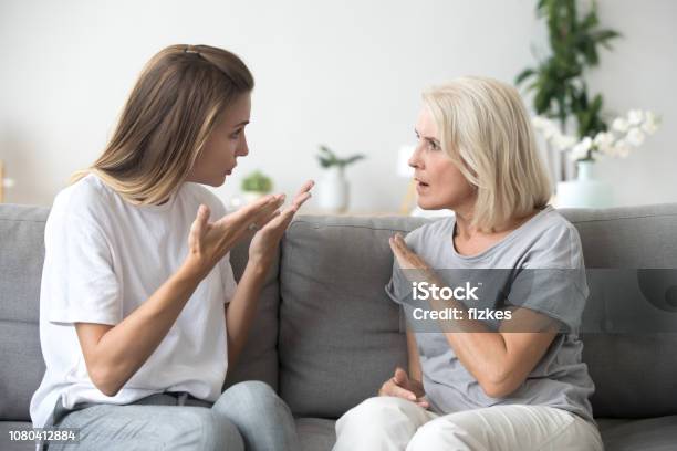 Angry Young Woman Having Disagreement With Annoyed Old Mother Stock Photo - Download Image Now