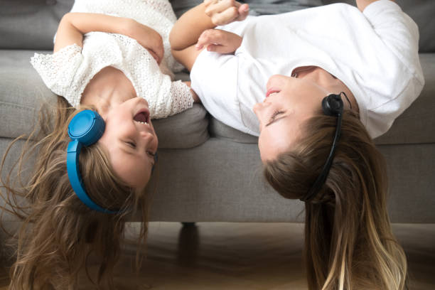 niño y madre acostado boca abajo en auriculares gozan de la música - fun time audio fotografías e imágenes de stock