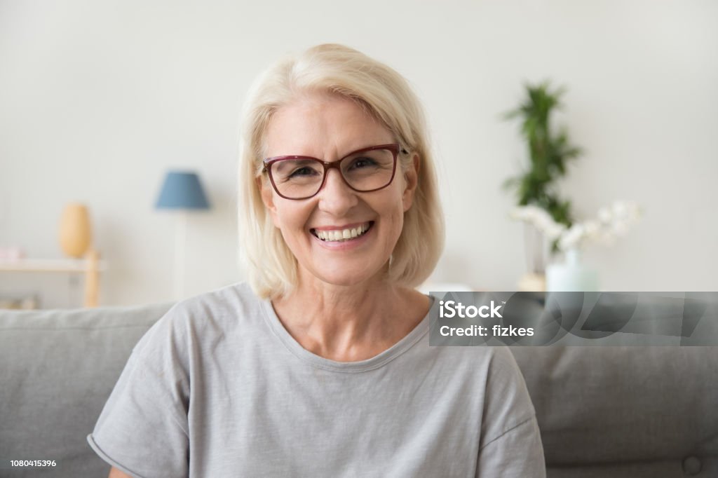 Sorridente donna dai capelli grigi maturi di mezza età che guarda la macchina fotografica - Foto stock royalty-free di Sorridere