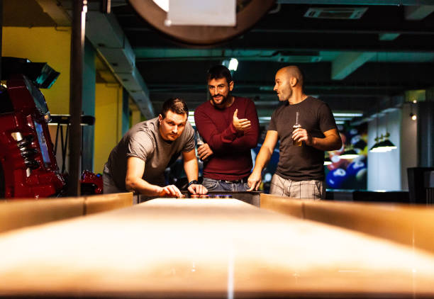 männer spielen shuffleboard in schwimmhalle - pool game pool table aiming men stock-fotos und bilder