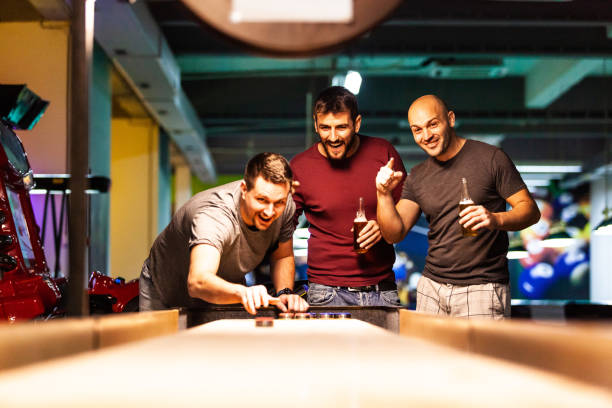 männer spielen shuffleboard in schwimmhalle - pool game pool table aiming men stock-fotos und bilder