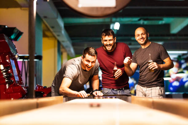 männer spielen shuffleboard in schwimmhalle - pool game pool table aiming men stock-fotos und bilder