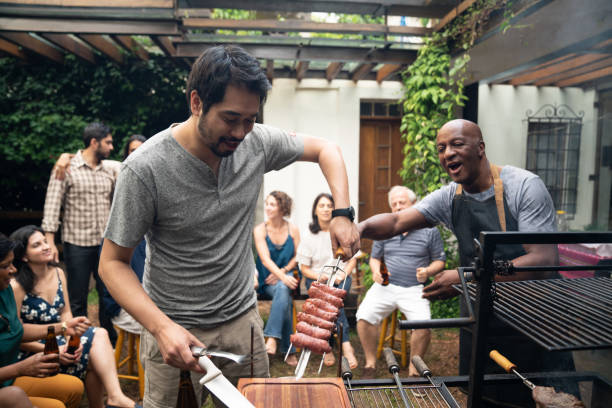 familiares y amigos disfrutando de una fiesta de barbacoa en casa - sausage barbecue grill barbecue cooking fotografías e imágenes de stock