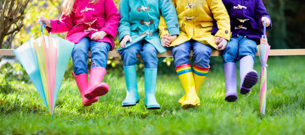 Kids in rain boots. Foot wear for children. Group of kids in rain boots. Colorful footwear for children. Boys and girl in rainbow wellies and duffle coat. Rainbow foot wear and clothing for autumn or winter. Rainy weather outerwear and fashion. mud photos stock pictures, royalty-free photos & images