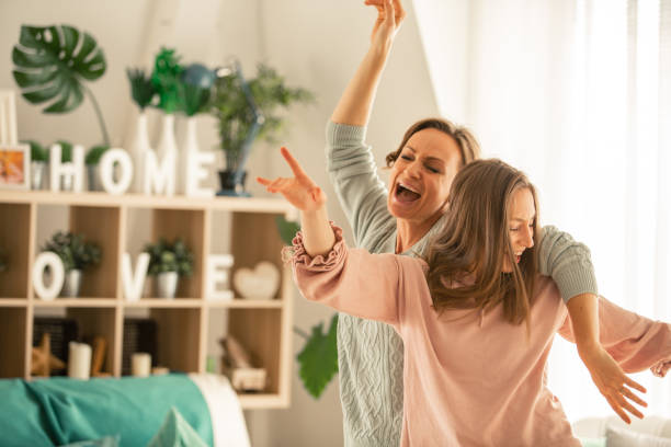 In the moment Mother and her daughter captured in the moment of pure joy and laughter while dancing and singing together in their living room. singing photos stock pictures, royalty-free photos & images