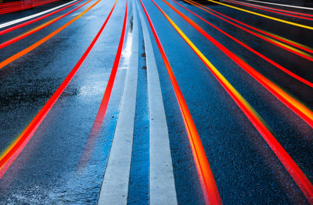 Rain wet asphalt road, arrows and motion blurred car