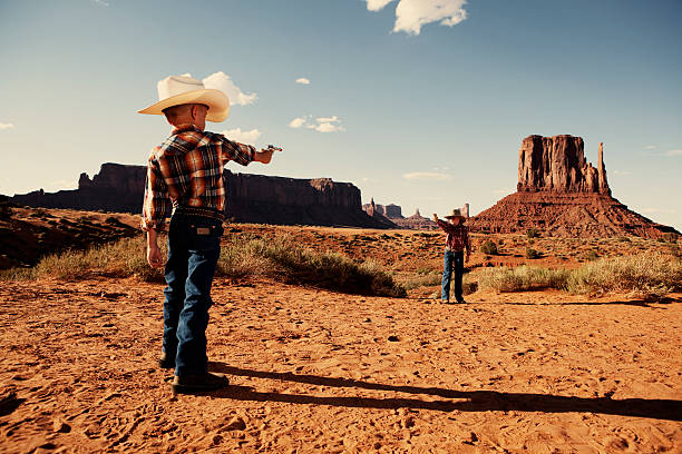 Gunfight Don't mess with the law. This young sheriff is ready to tame the Wild West. Taken in historical Monument Valley. wild west gunfight stock pictures, royalty-free photos & images