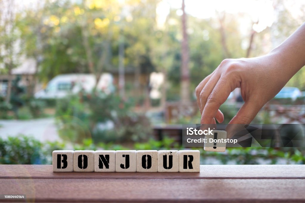 BONJOUR ! Concept with Hand and alphabet blocks BONJOUR !  Concept with alphabet blocks on wooden table. Alphabet Stock Photo