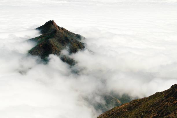 istock A mountain peak rises above a thick layer of clouds 1080442814