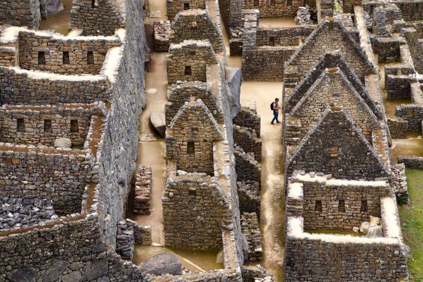 un uomo vaga tra le rovine dell'antica città inca di machu picchu in perù - machu picchu foto e immagini stock