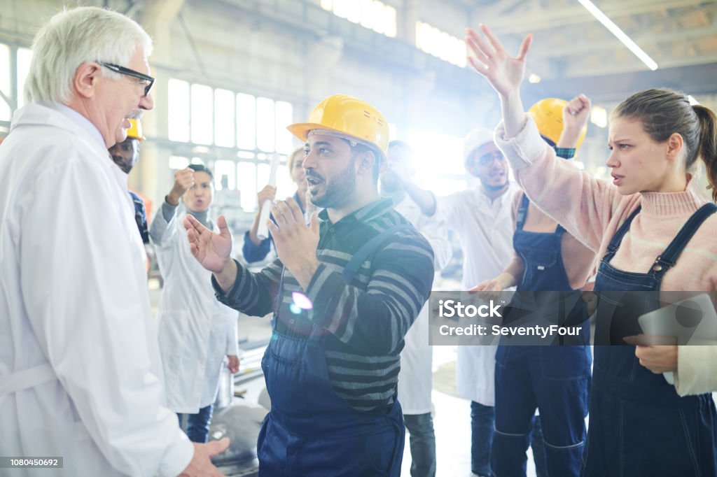 Angry Worker Talking to Boss Portrait of female factory worker talking to mature manager during strike on industrial plant, copy space Labor Union Stock Photo