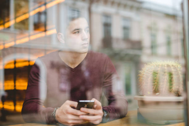 l'uomo seduto con un telefono sopra la finestra in un bar - business blurred motion text messaging defocused foto e immagini stock