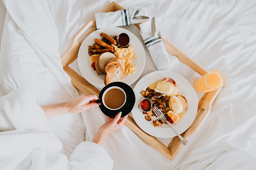 Woman in bed enjoying breakfast.