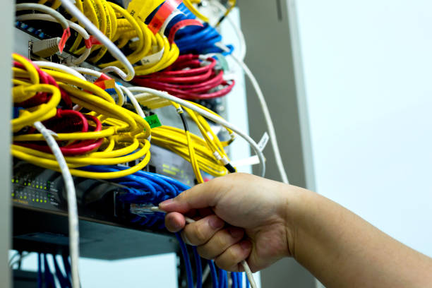 istock A hand holding LAN cord with Ethernet cables and Network switching hub LAN System Communication 1080475850
