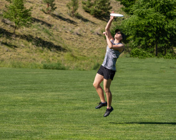 istock Young woman leaps to catch flying disc 1080503756