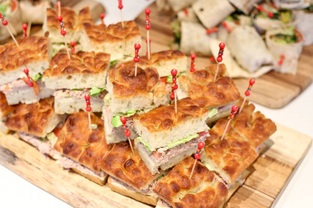 A tray of sandwiches at a buffet. A party platter of ham, turkey and chicken sandwiches. Freshy made sandwiches