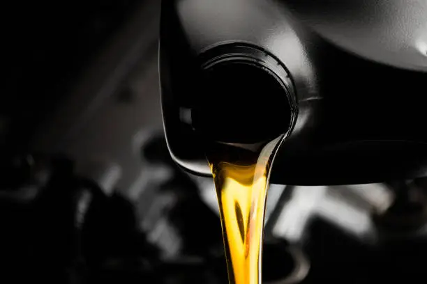 Pouring oil motor car  lubricant  from black bottle on engine background , service oil change auto repair shop