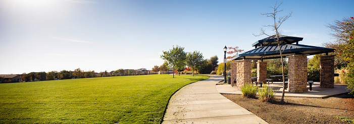 New Public Suburban park in California with stone gazebo panorama and a winding pathway with a large lawn to the left.