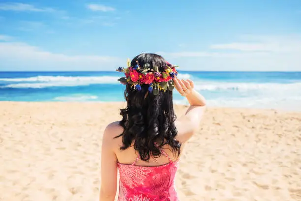 Wearing floral Haku lei on head and watching Sandy beach Hawaii