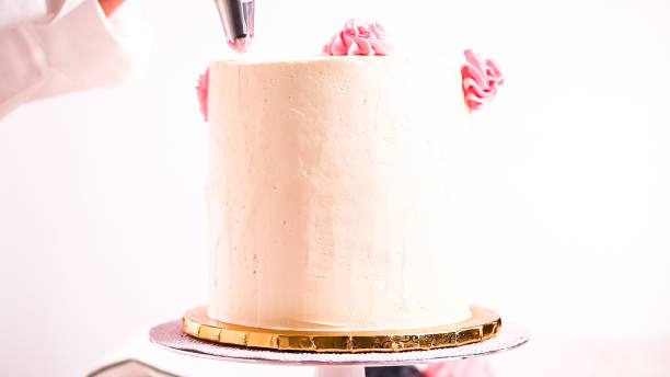 istock Baker piping pastel color buttercream rosettes on a white cake 1080590920