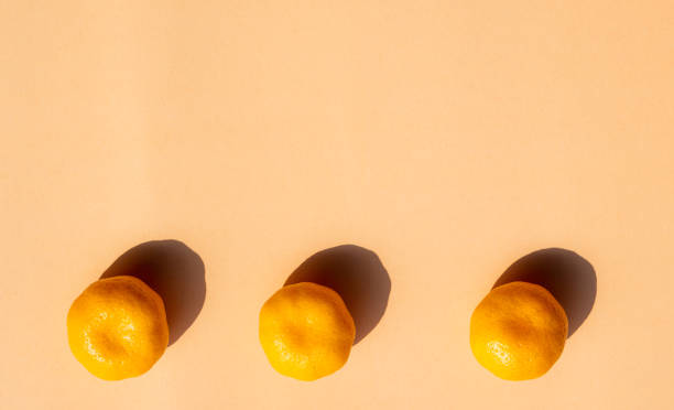istock 3 whole oranges with strong shadow on orange background, copy space 1080595356