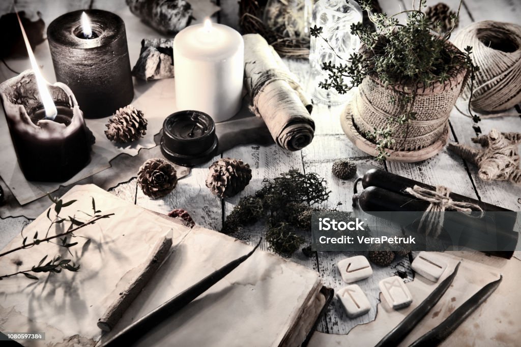 Still life with black and white candles, runes, cones and open diary book on table Magic gothic ritual. Wicca, esoteric and occult background with vintage objects Wizard Stock Photo