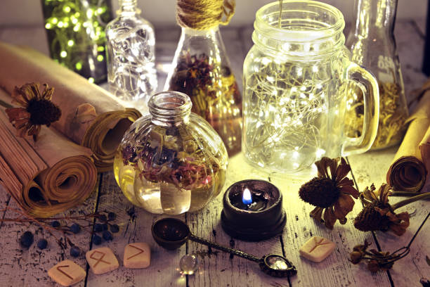 istock Lighting bottles with runes, seeds, herbs and old manuscripts on table 1080601356