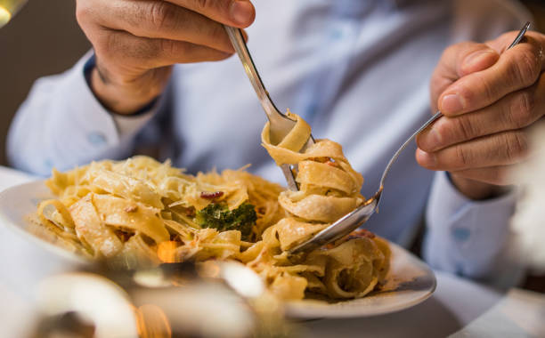 primo piatto di uomo irriconoscibile che mangia pasta per pranzo. - cibo italiano foto e immagini stock