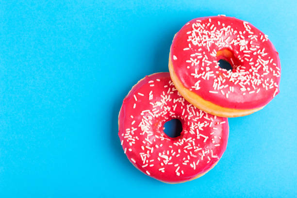 istock Two delicious pink donuts with sprinkle on bright blue background 1080619654