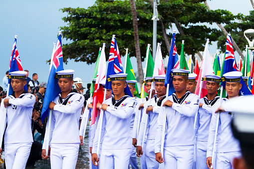 Asean fleet parade in Pattaya and capture of thai navy soldiers walking along Beach Road with Asean flags of participating nations. Row in foreground is holding up australian flags.